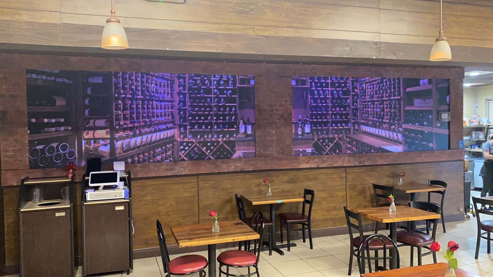Salón de Villa Parrilla preparado para fiesta, con rosas en las mesas y mural de bodega